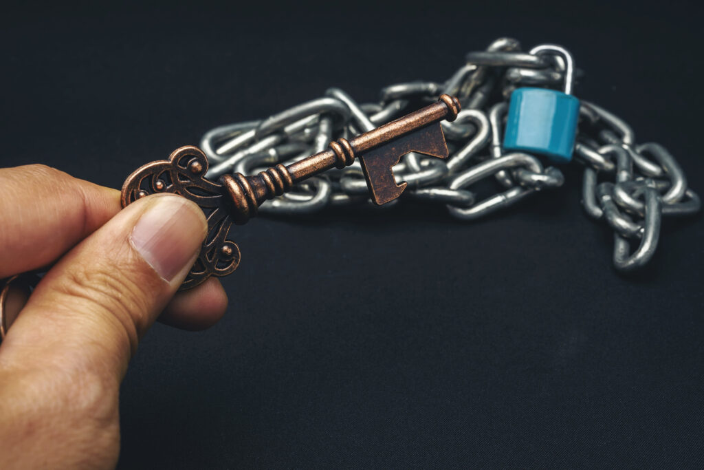 a man's hand holding an old key with a chain with a background.